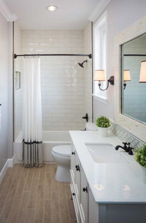 Phòng tắm có tông màu trắng chủ đạo ở tường và trần, phần sàn ốp gỗ màu be hài hoà, điểm nhấn là một số thiết bị màu đen tạo sự tương phản và tránh nhàm chán cùng một vài chậu cây nhỏ.