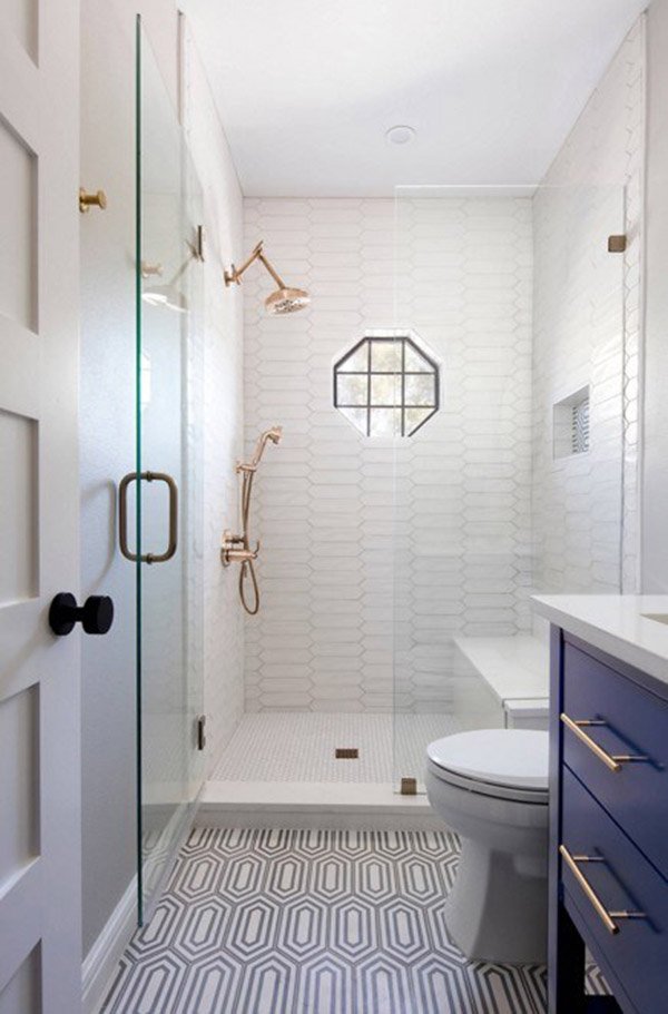 Phòng tắm tông trắng với phần gạch ốp có hoạ tiết khá độc đáo, một số thiết bị vệ sinh có màu vàng kim loại sang trọng, khu vực vòi sen còn có cửa kính giúp chắn nước bắn ra ngoài.
